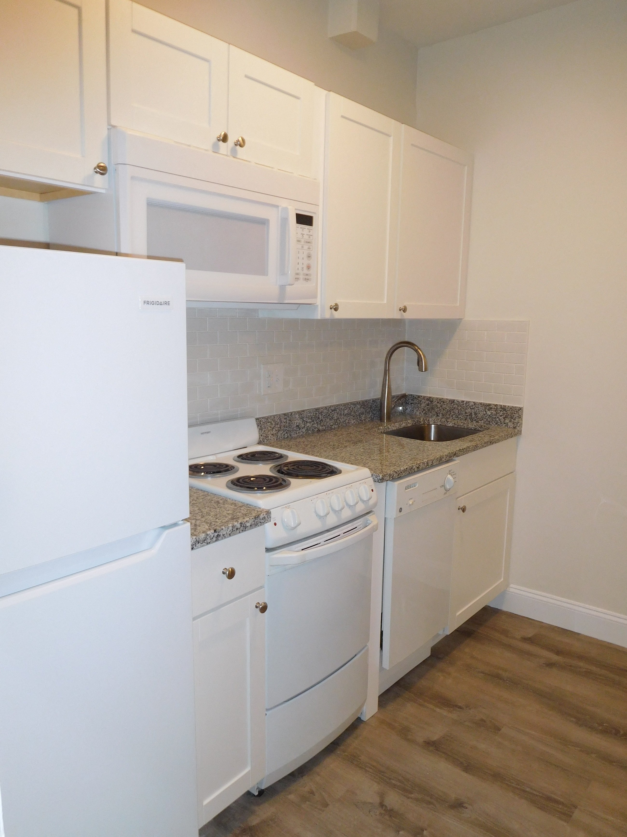 a kitchen with white appliances and granite counter tops and white cabinets